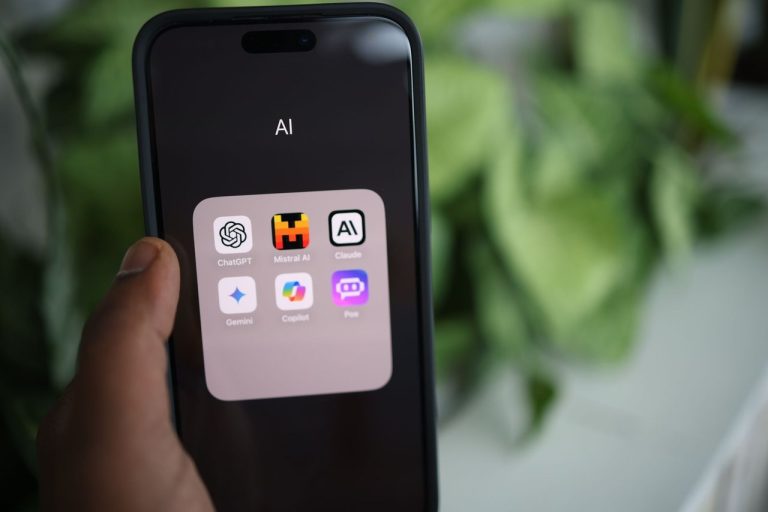 Close-up de uma mão segurando um smartphone com aplicativos de inteligência artificial na tela