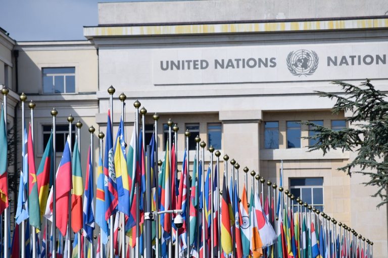 Bandeiras de vários países hasteadas diante do escritório da ONU em Genebra, simbolizando cooperação internacional